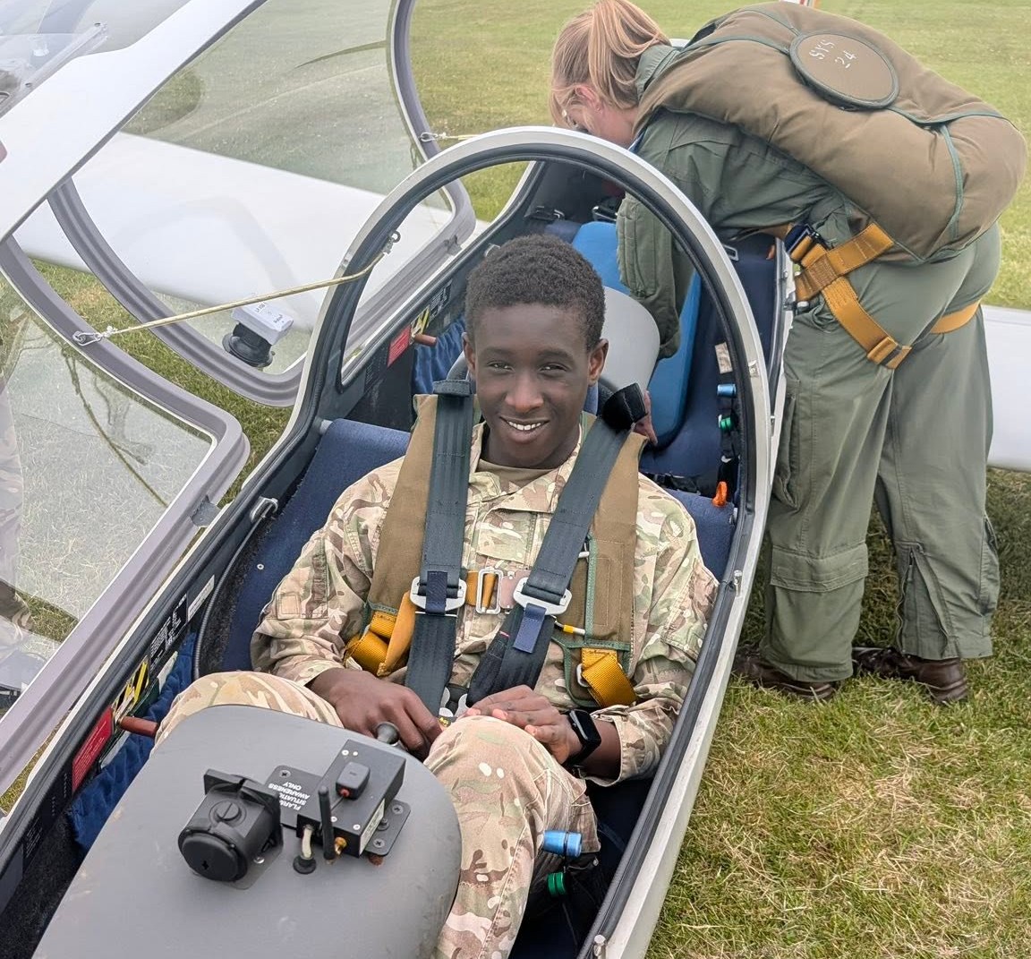 A smiling CCF cadet student sitting in a glider cockpit, showcasing exciting career exploration activities and co-curricular opportunities.