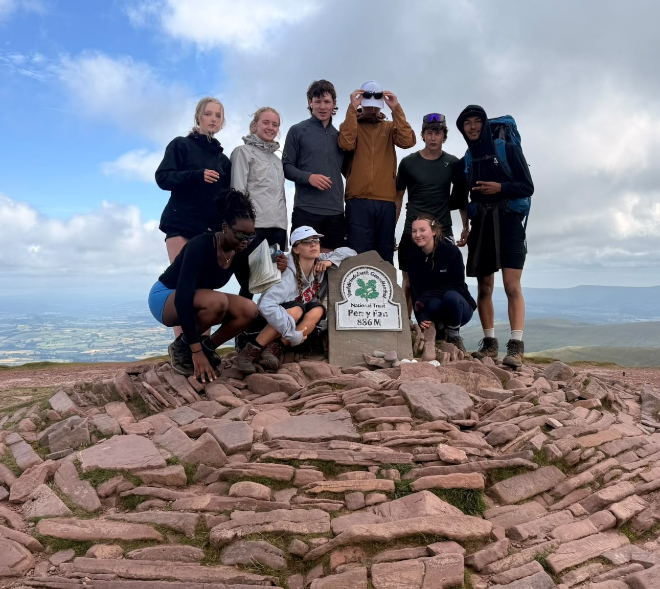 A group of Duke of Edinburgh Award students celebrating at a mountain summit, highlighting the benefits of co-curricular activities in school for personal growth.